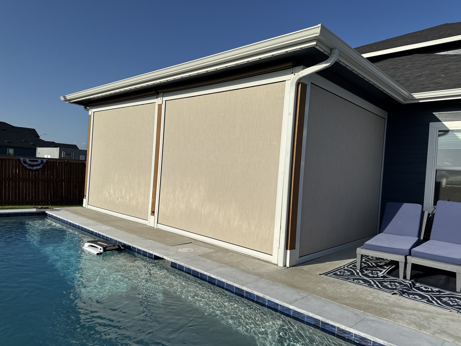 Motorized patio shades installed beside a backyard pool
